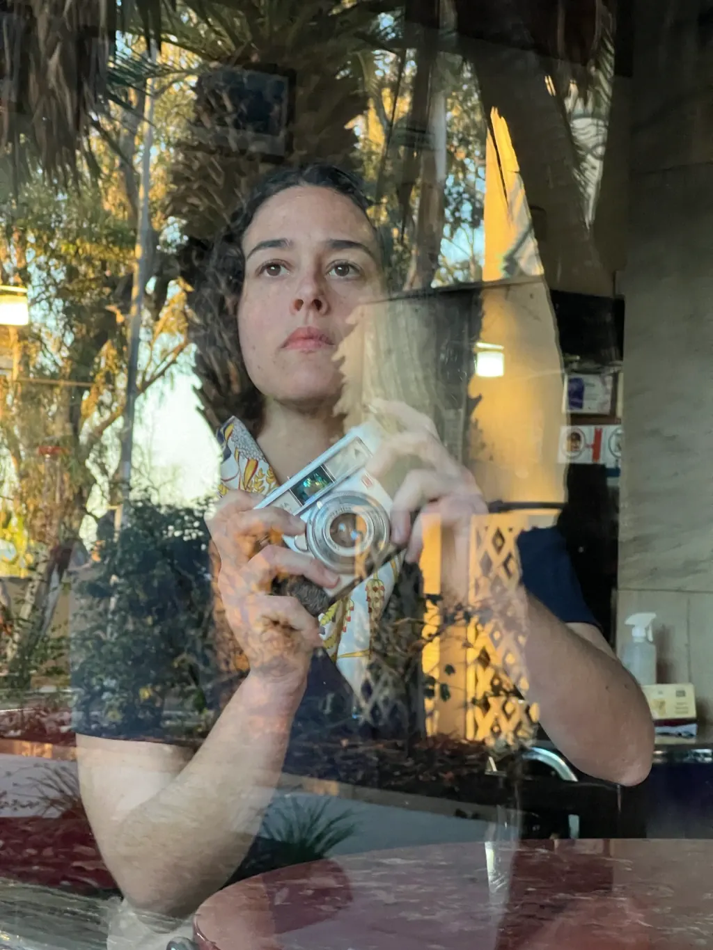 Alba Berrocal fotografiándose con una cámara antigua, reflejada en un cristal